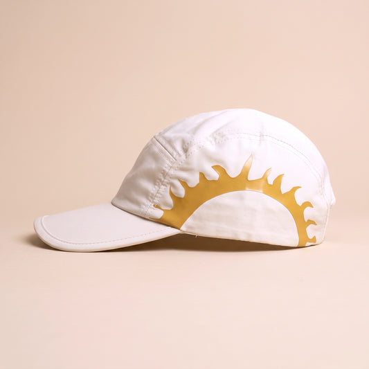 Side view of the cream SOL Cap with the full gold sunburst print across the panel